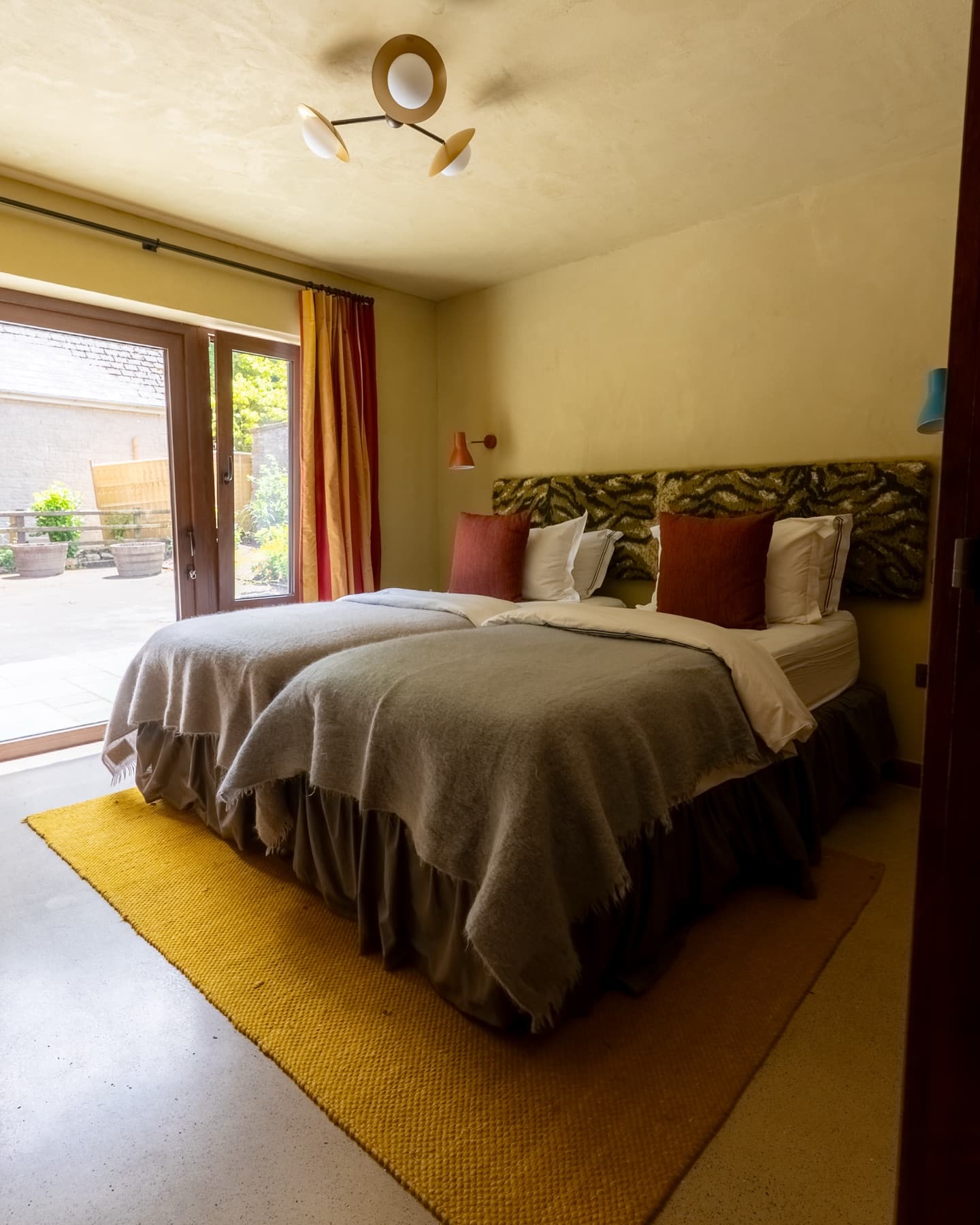 Ochre bedroom with twin beds, wool blankets and doors to the terrace