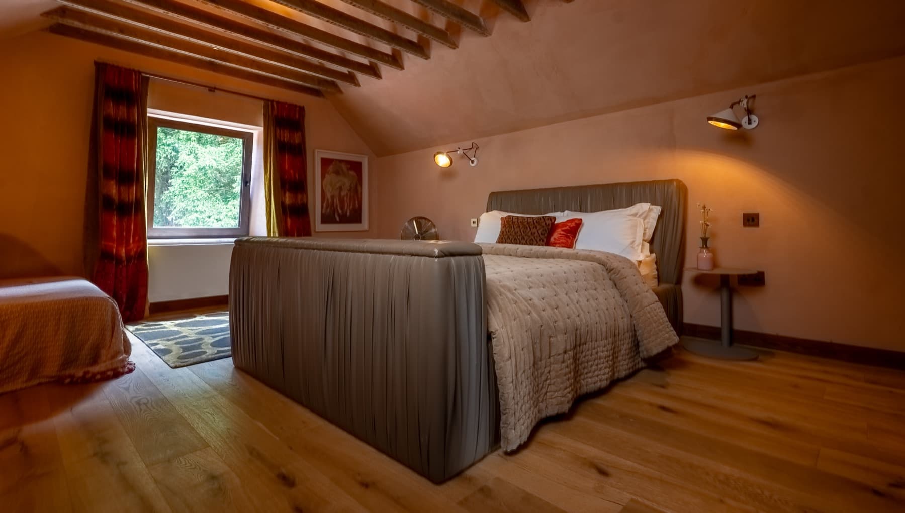 Bedroom with mineral-render walls, upholstered bed and exposed beams
