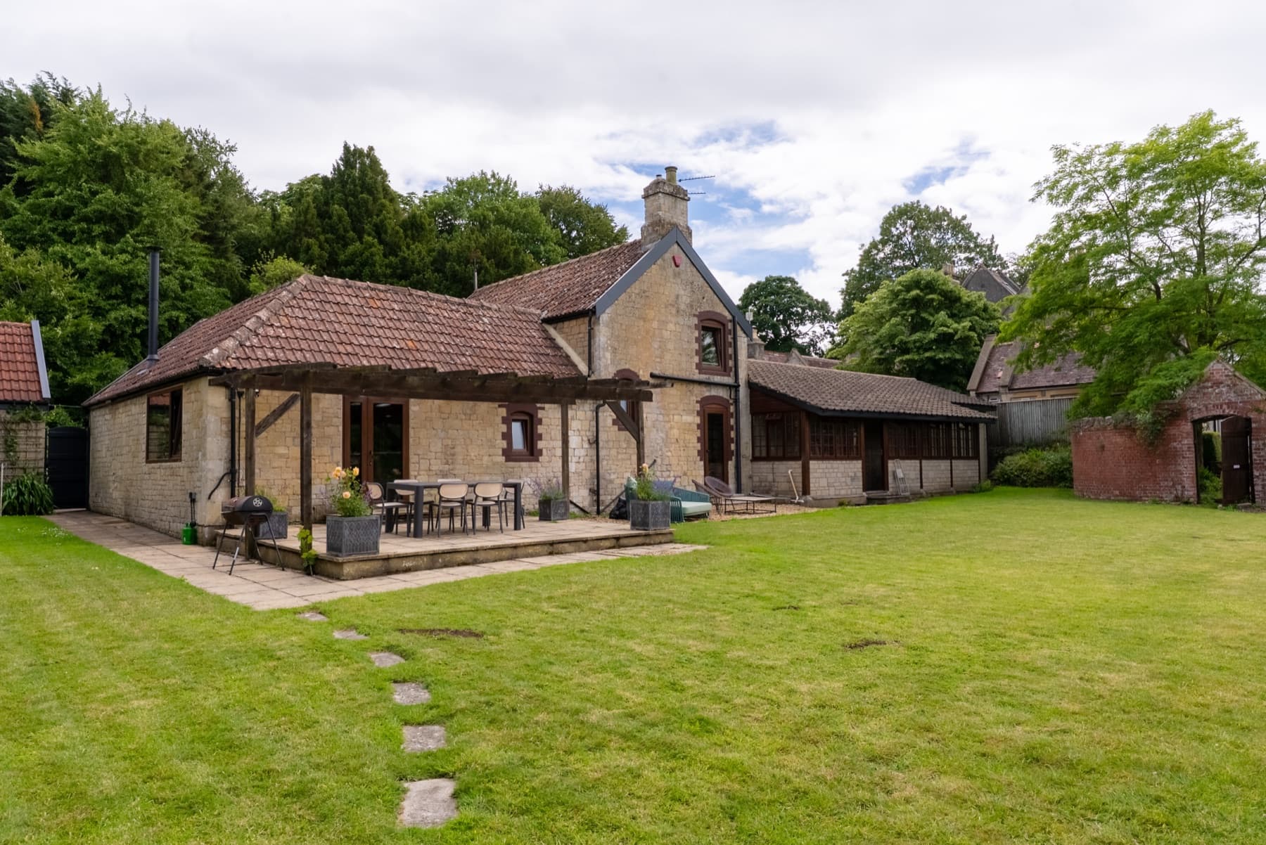 The Old Stables seen from the lawn, pergola terrace and walled garden