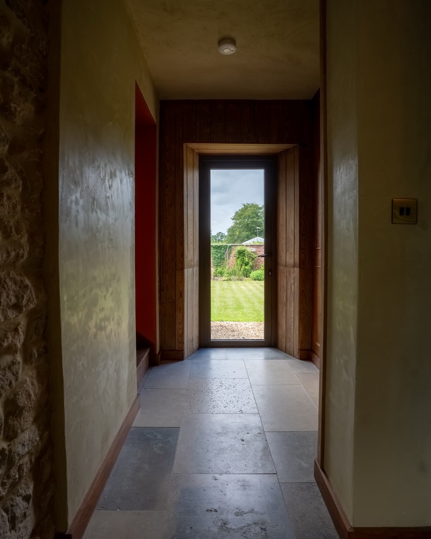 Stone-flagged corridor with a glazed door onto the walled lawn