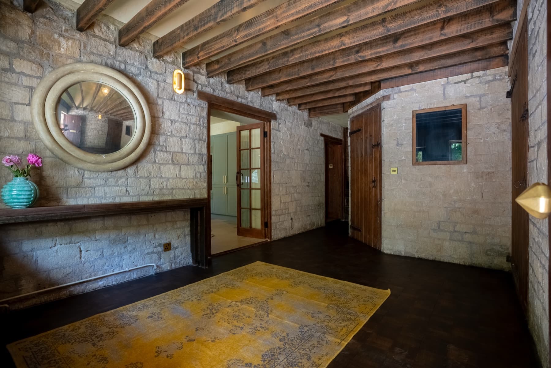 Stone-walled hall with a convex mirror under exposed beams