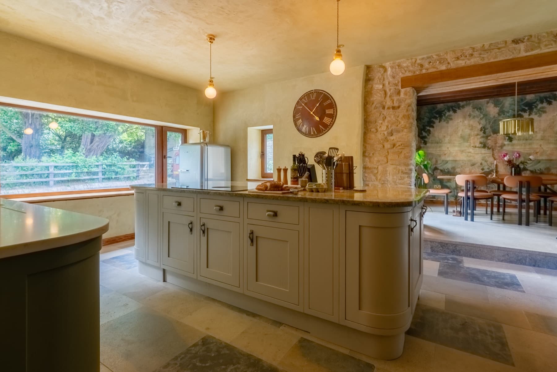 Kitchen island under pendant lights, lime plaster walls and stone pier