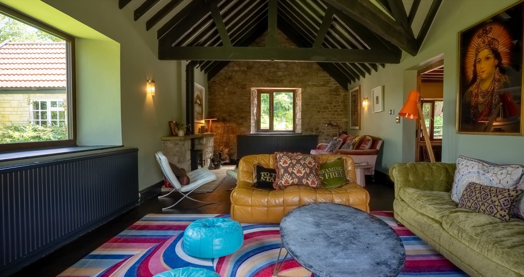The Old Stables living room, vaulted beams, log burner and exposed stone gable