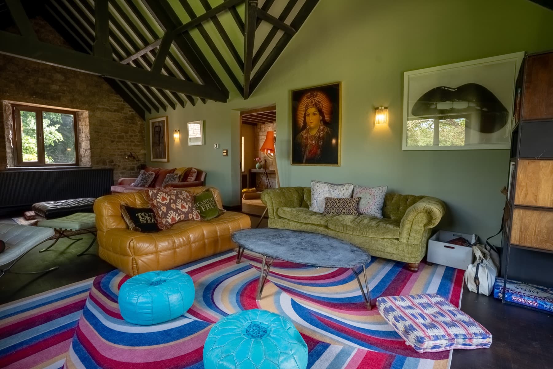 Living room under the vaulted roof, leather and velvet sofas on a striped rug