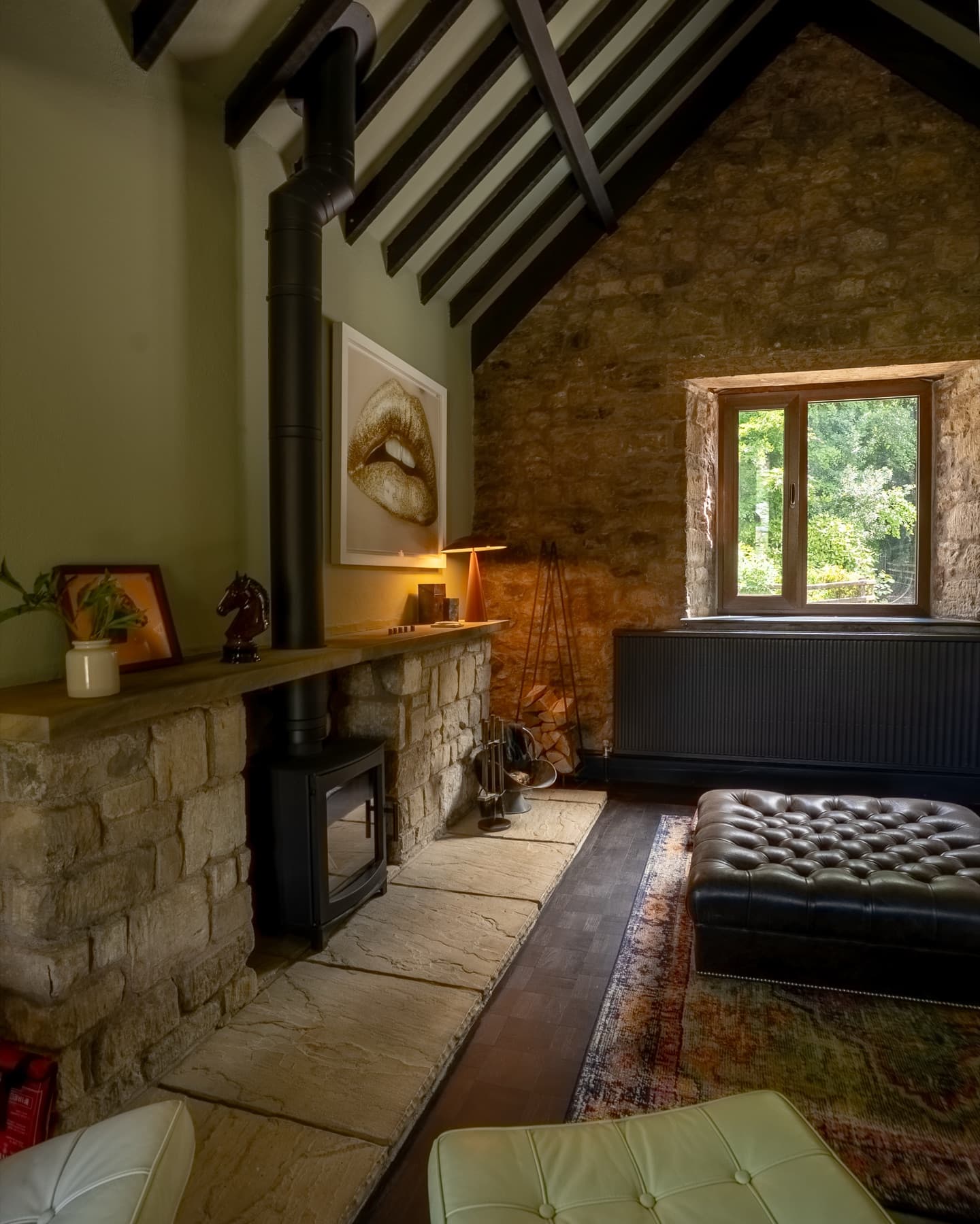 Log burner set into a stone chimney breast under the beamed gable