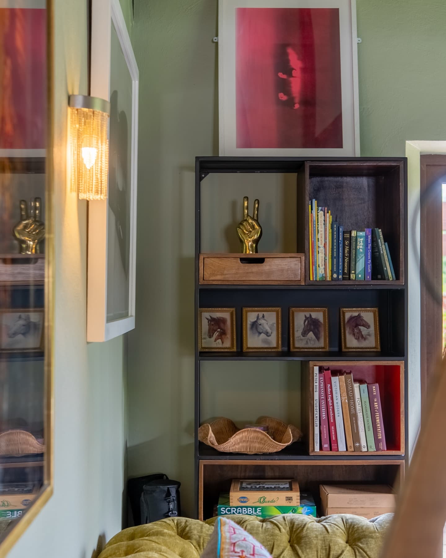 Shelves of books, board games and framed horse studies in the snug